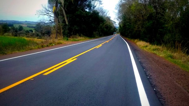 A foto mostra um trecho de rodovia pavimentado e sinalizado.