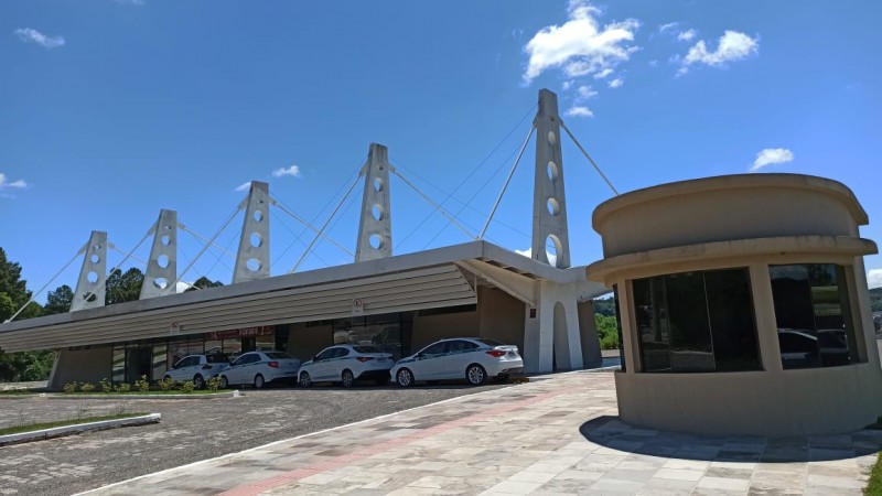 Na imagem aparece a rodoviária. No estacionamento dela estão carros estacionados.
