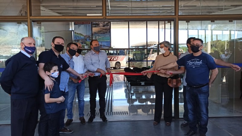 Na imagem aparece a cerimônia clássica de corte de fita para a inauguração da rodoviária. Estão presentes nela autoridades locais e os vencedores da licitação. Ao todo, são 7 homens adultos, um menino e uma mulher.